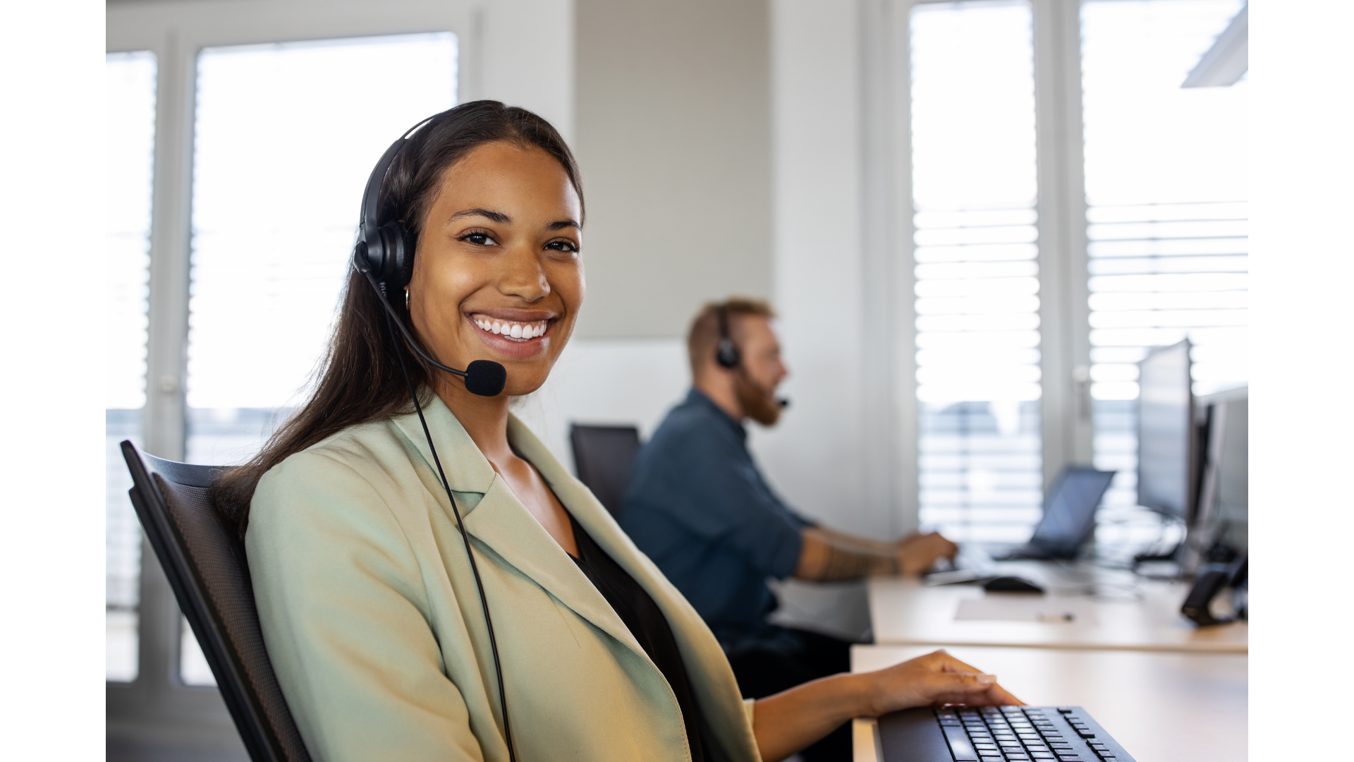 Smiling customer service representative wearing a headset in a modern support office