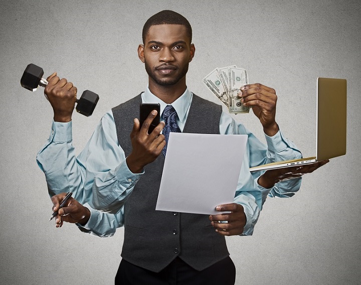 Overwhelmed entrepreneur juggling phone, laptop, cash, paperwork and a dumbbell
